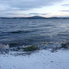 En mörk sjö med berg i bakgrunden.